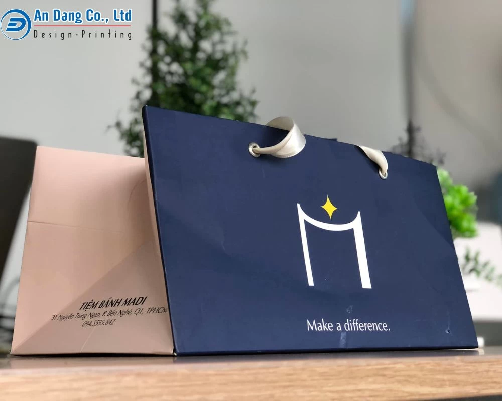 Mẫu túi giấy với logo chữ M ấn tượng cùng câu slogan đơn giản, phần quai được làm bằng lụa sang trọng